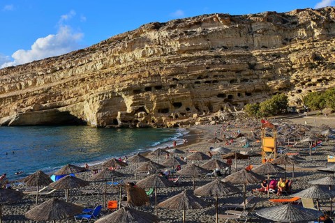 Neolithic caves, former hippie paradise, a sunny beach with umbrellas in front of impressive ocean