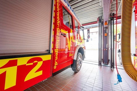 Red fire engine in a large garage room with visible hose on the ceiling, Gechingen fire department,