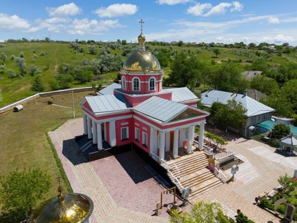 Orthodox village church with golden dome and blooming trees under a blue sky, aerial view, St.