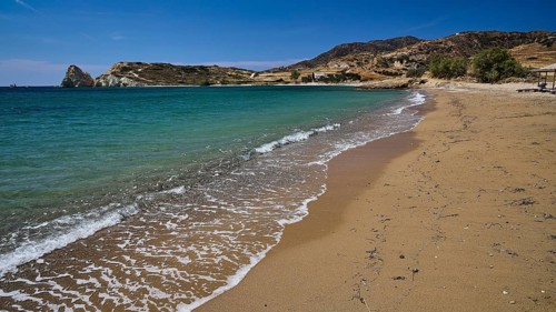 Empty beach with gentle waves, golden sand and blue water under clear skies, Mavorspilia Beach,