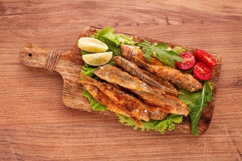Fried crispy red mullet fish, on a wooden chopping board, with lime, no people