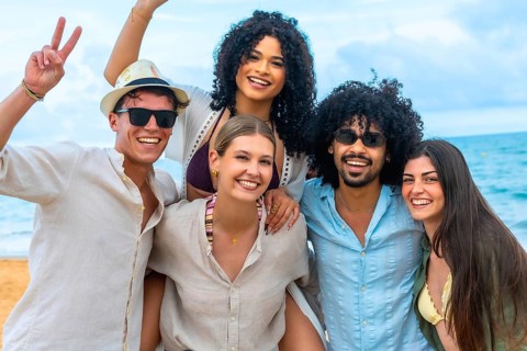 Diverse group of young adult friends enjoying a joyful summer holiday together, embracing on the