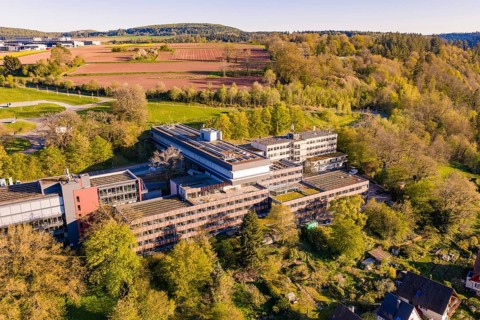 Industrial building complex with solar cells between fields and trees in an environment close to