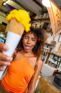 Young woman with curly hair showing a playful expression and sticking out her tongue while holding