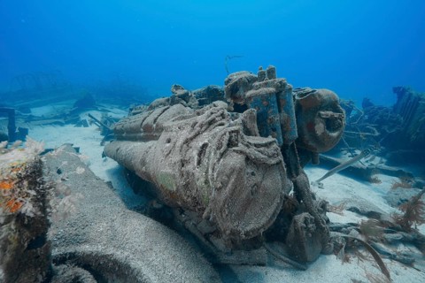Rusted remains of an engine on the seabed surrounded by sand and wreckage, meteor wreck dive site,