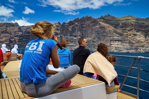 Los Gigantes, group of people sitting on a boat floating off a rocky coast, whale watching boat