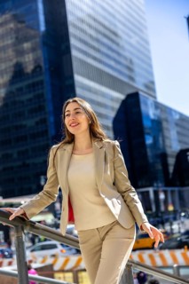 Young businesswoman standing outdoors in new york city, smiling and looking ahead with