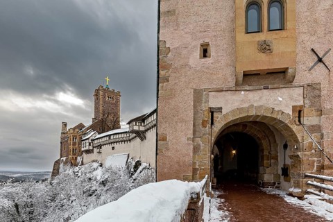 Castle with tower and archway surrounded by snow under a dramatic sky, The Wartburg near Eisenach
