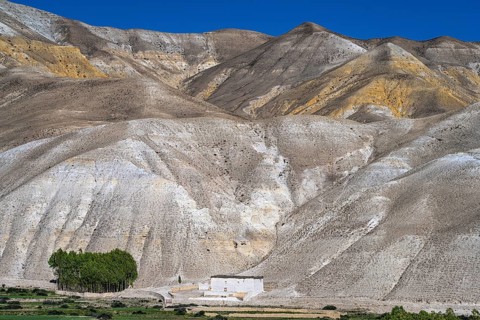 Traditional house in front of mountain landscape, erosion landscape near Lo Manthang, Mustang,