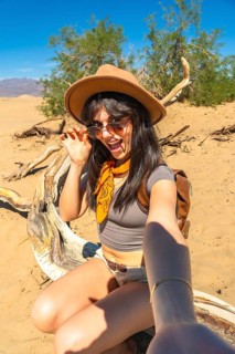 Adventure traveler woman exploring dry arid mesquite flat sand dunes in death valley national park,