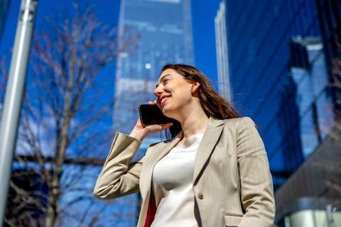 Professional young businesswoman having a smiling conversation on her smartphone in a vibrant urban