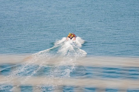A motor boat draws waves by itself as it travels quickly across the open sea, Howth, Ireland