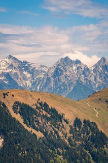 Snowy mountain peaks with forests and a winding hiking trail in hilly surroundings, Hahnenkamm,
