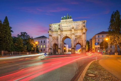 Long exposure of the illuminated Siegestor in Munich, Bavaria, Germany, featuring colorful red and
