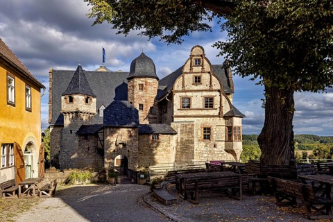 Cosy atmosphere of a castle complex with seating under a tree, The Upper Castle of Kranichfeld in
