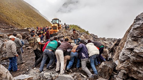 People work together to move a rock, with a tractor on a foggy mountain road, rockslide on the pass