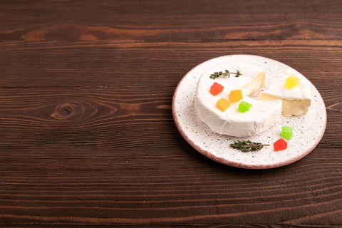 White Camembert mold cheese on brown wooden background, side view, copy space
