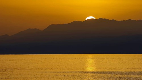 Sunset over mountains with golden light reflecting in calm sea, Matala, South Coast, Crete, Greek