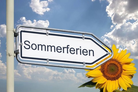 (photo montage) Direction arrow with text SUMMER VACATION against a blue sky and sunflower on the