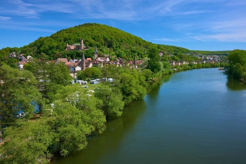 An idyllic riverside village with green forests and hills under a blue sky, Main, Gemünden am Main,