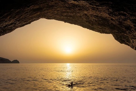 Seen from the Blue Grotto off Cabrera (Majorca), the sun sets on the horizon over the sea, Cabrera,
