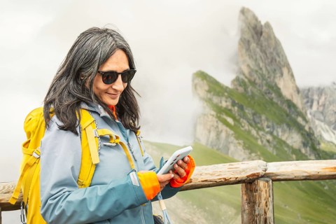 Smiling woman hiker checking mobile GPS navigation app type message, use social media on smartphone