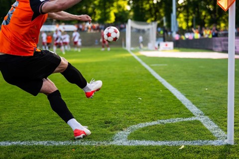 A soccer player kicking a ball from the corner line during a professional football match on a