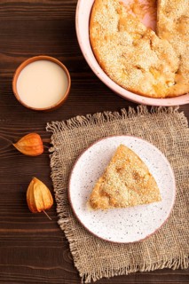 Apple Charlotte cake on brown wooden background and linen textile, cup of milk, top view, flat lay,