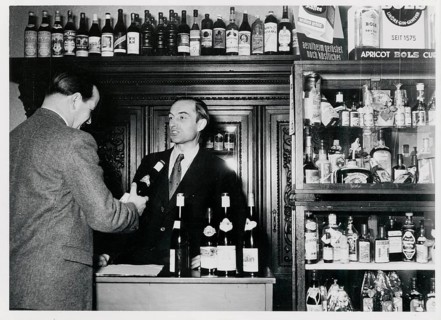 West Berlin, shop for alcoholic beverages, pub, A bartender serves a man in front of a shelf full