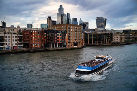 View of Millennium Bridge, pedestrian suspension bridge on tour boat with tourists on the Thames,