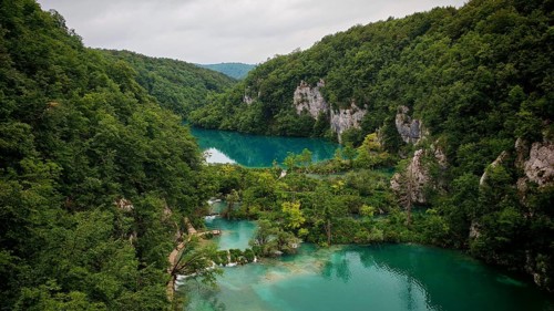 An aerial view shows green basin-like turquoise blue lakes, framed by rocky valleys and magnificent