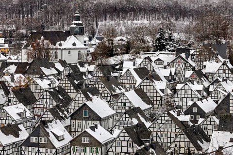 Close-up of snow-covered half-timbered houses and a church in the wintry village in front of the