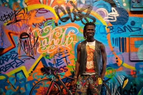Young man, dark-skinned, African, smiling, posing in front of graffiti, legal, temporary graffiti