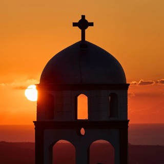 Church of the Archangel Taxiarchis, A bell tower at the center of a lively sunset with the sun