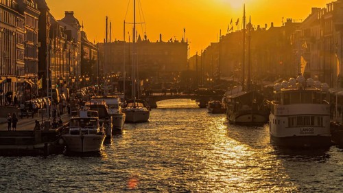 Sonnenuntergang über einem städtischen Kanal mit gleißendem Wasser und Booten im warmen Licht,