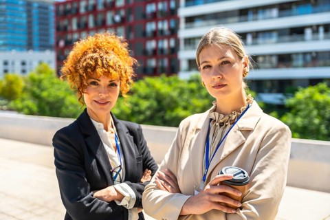 Two confident businesswomen standing side by side, engaging in a professional partnership,