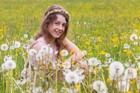 Portrait of a smiling girl sitting in a flower meadow, Mondsee, Salzkammergut, Austria