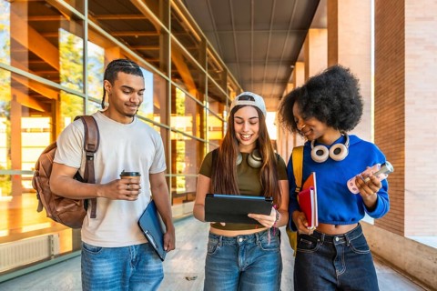 Diverse group of young university students walking together on campus, carrying backpacks, books,