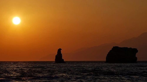 Calm sunset over the sea with a distinctive rock and mountains in the distance, sunset, south of