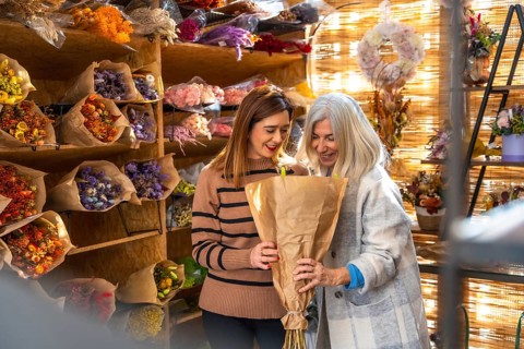 Smiling mother and daughter in a cozy flower shop sharing joy while arranging and selling artisanal