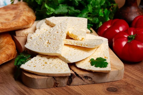 Georgian sliced cheese, on a wooden chopping board, with tomatoes with herbs and lavash, rustic