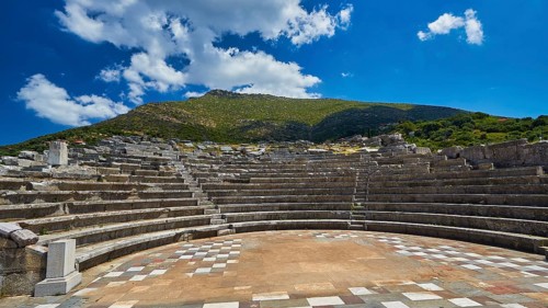 Ecclesiasterion, ancient amphitheatre with many rows of seats under blue sky with white clouds,