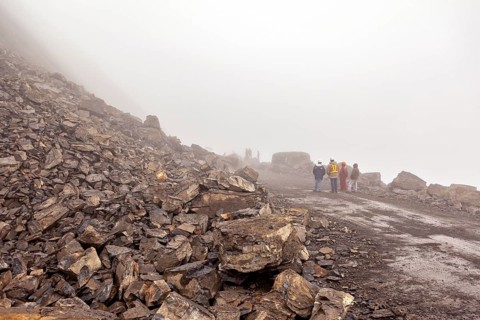 Construction workers stand on a rocky road in a foggy environment, rockslide on the pass road