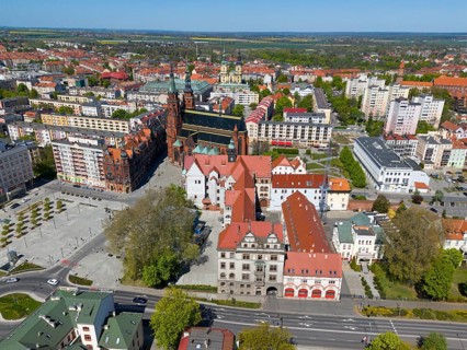 Historic city center with church surrounded by colorful buildings and green vegetation, bird's eye