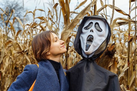 Woman looking at an effigy with a mask of death in a cornfield in Halloween