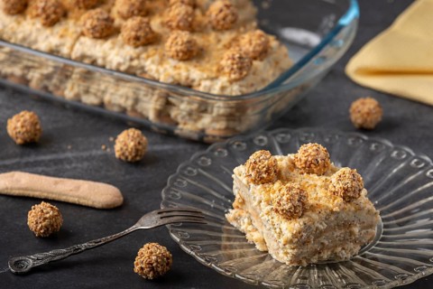 A piece of nutty tiramisu on a plate with fork ready to eat
