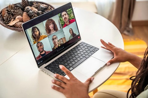 Woman's hands resting on a laptop during an online group therapy session, connecting diverse