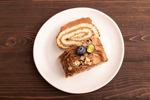 Sweet loaf with cream and caramel on brown wooden background, close up, top view, flat lay