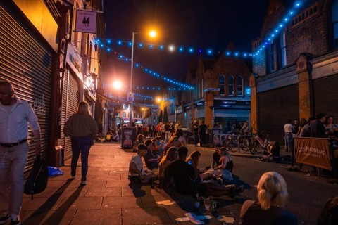 People sitting on the street at night surrounded by blue and orange lights, Nightlife, Dublin,