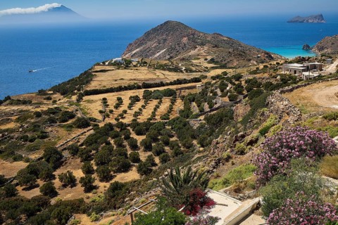 Green hills and vegetation, rocky coasts and blue sea in the distance, Plaka, main town on Milos,